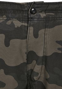 Pantalones de camuflaje en tejido de color verde oscuro y negro, con cierre de botón, costuras superiores y una textura suave y lisa.