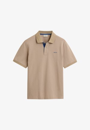 Beżowa koszulka polo z kontrastowym niebieskim wykończeniem dekoltu. Krótkie rękawy, miękka tkanina i haftowane logo w kolorze niebieskim. Klasyczny krój i czysty design.