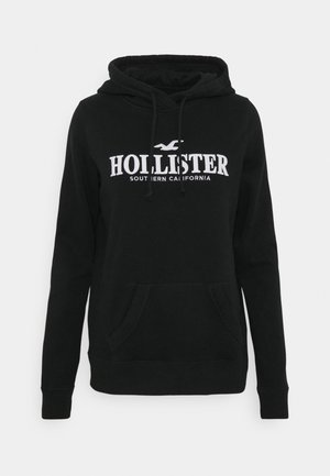 Czarna bluza z kapturem z białym logo "Hollister Southern California" i przednią kieszenią kangurką, pokazana na jednolitym tle.