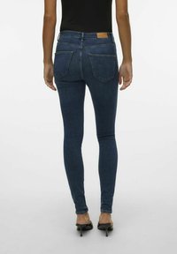 Jeans skinny in denim blu scuro con vita alta e due tasche posteriori. Design a gamba affusolata e leggero stretch per il comfort.
