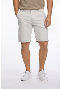 Ljust grå bomullsshorts med uppvikt fåll, sidfickor och knäppning, kombinerat med vita sneakers på en neutral bakgrund.