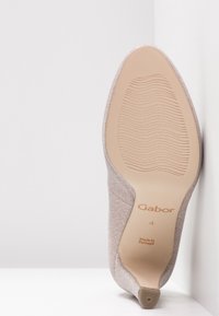 Talons Gabor beige clair montrant un dessus texturé, une semelle lisse et un détail de logo. La semelle présente des motifs nervurés pour une meilleure adhérence.