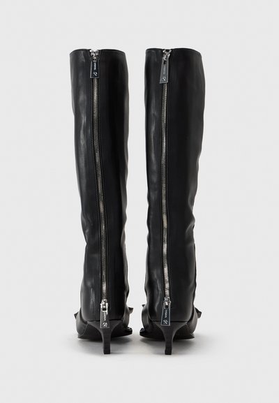 Botas de cuero negro hasta la rodilla con textura suave, que cuentan con cremalleras laterales plateadas y un tacón pequeño. Sin patrones visibles ni acentos adicionales.