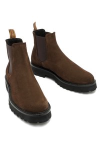 Brązowe zamszowe botki Chelsea mają elastyczne boczne panele, solidną czarną gumową podeszwę oraz pętelkę ułatwiającą zakładanie.