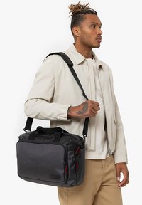 Borsa a tracolla nera e grigia con tessuto testurizzato, doppio manico, tracolla regolabile e dettagli in zip rossi.