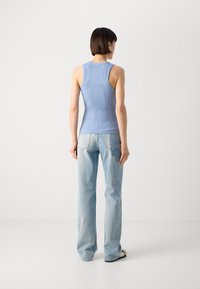 Hellblaues, geripptes Tanktop mit taillierter Silhouette, kombiniert mit locker sitzenden hellblauen Jeans, die am unteren Ende leicht ausgestellt sind.