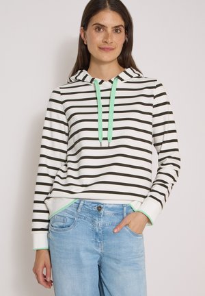 Femme aux longs cheveux foncés portant un sweat à capuche blanc avec des rayures horizontales noires et des cordons vert menthe, associé à un jean bleu clair.