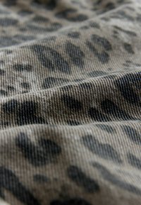 Leopard print fabric with shades of beige and dark gray. Textured surface shows a soft, ribbed weave with varying pattern sizes.