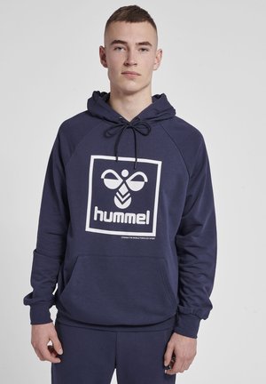 Mörkblå hoodie i mjukt tyg, med en logo på framsidan, dragsko på huvan och kenguruficka. Ribbad mudd och fåll fulländar designen.
