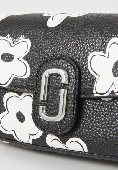 Borsa a mano in pelle nera con un motivo floreale bianco. Presenta un fermo metallico e una superficie testurizzata. Il logo di Marc Jacobs è visibile.
