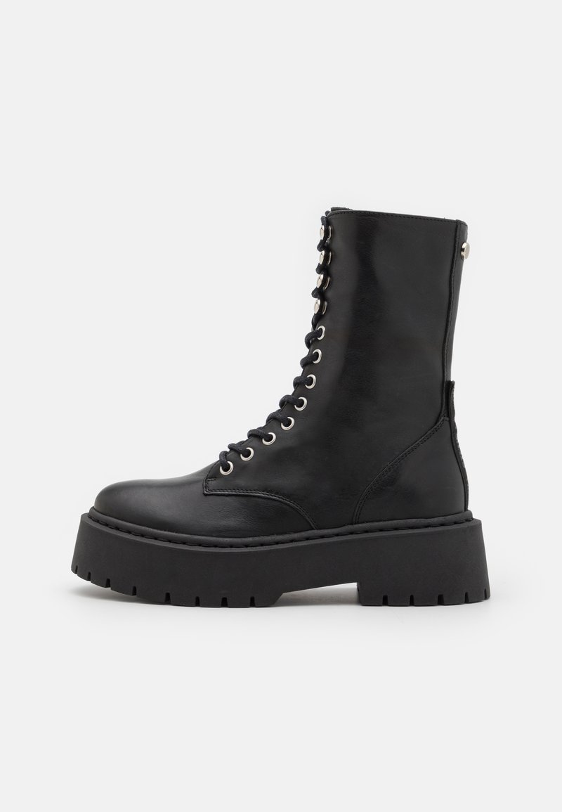 Botte de combat en cuir noir avec un laçage sur le devant, des œillets métalliques, et une semelle épaisse noire avec une texture nervurée.