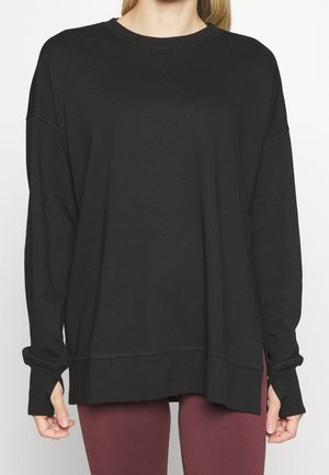 Schwarzes Sweatshirt mit langen Ärmeln, lockerer Passform, rundem Halsausschnitt, überschnittenen Schultern und seitlichen Schlitzen, aus weichem, dehnbarem Stoff.