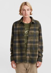 Grøn og marineblå ternet flannel skjorte med knaplukning fortil, brystlomme og blød tekstur, båret over en mørkegrøn grafik t-shirt.