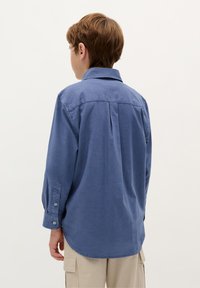 Blaues Langarmhemd mit button-down Kragen, ausgestattet mit einer Yoke-Detail und einer lockeren Passform, aus strukturiertem Stoff gefertigt.