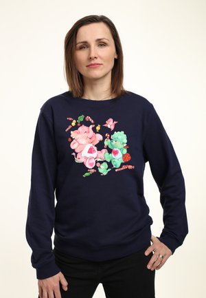 Marineblauwe sweatshirt met een kleurrijke cartoonachtige print van een olifant en een beer met snoepjes en bloemen. Zachte stof, lange mouwen, relaxte pasvorm.