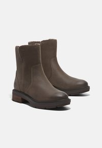 Brune lær ankle støvler med en glat finish, luksuriøs indvendig foring, blokhæle og let mønster på gummisålen. Timberland-logo på siden.