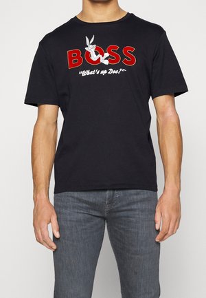 Schwarzes Baumwoll-T-Shirt mit einem Grafikdesign, das "BOSS" in roter Schrift und Bugs Bunny mit dem Spruch "Was geht, Doc?" in Weiß zeigt.