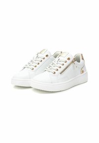 Zapatillas blancas hechas de material sintético, con punta redondeada, acentos dorados y detalle de cremallera en el lateral. Suela blanca gruesa y diseño de cordones.