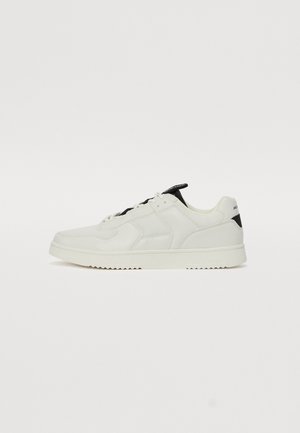 Hvide sneakers med en kombination af glat og tekstureret materiale, sorte akcenter på hælen, rundt tådesign og et syet mønster.