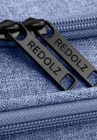 Tejido azul texturizado con tiradores de cremallera negros etiquetados "REDOLZ", con un diseño sencillo y un recorrido de cremallera suave.
