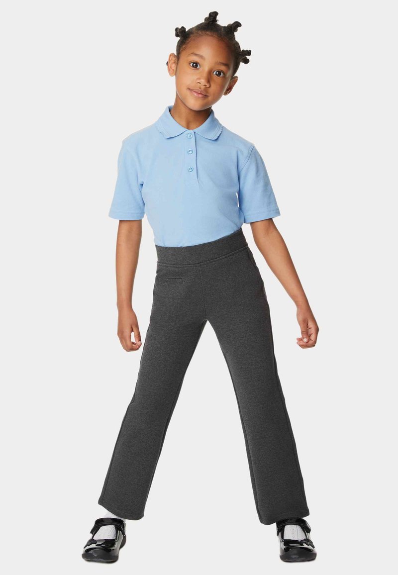 Polo de color azul claro con tres botones, combinado con pantalones oscuros de algodón elástico que tienen una cintura alta y bolsillos laterales. Zapatos negros.