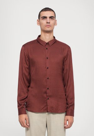 Burgundy button-up shirt with white polka dots, long sleeves, and a pointed collar. Features black buttons and a smooth, slightly shiny texture.