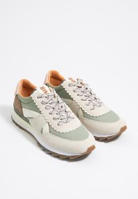 Sneakers met een beige suède en mesh bovenwerk, olijfgroene accenten, een crèmekleurige rubberen loopzool en contrasterende veters. Schulpdesign detail.