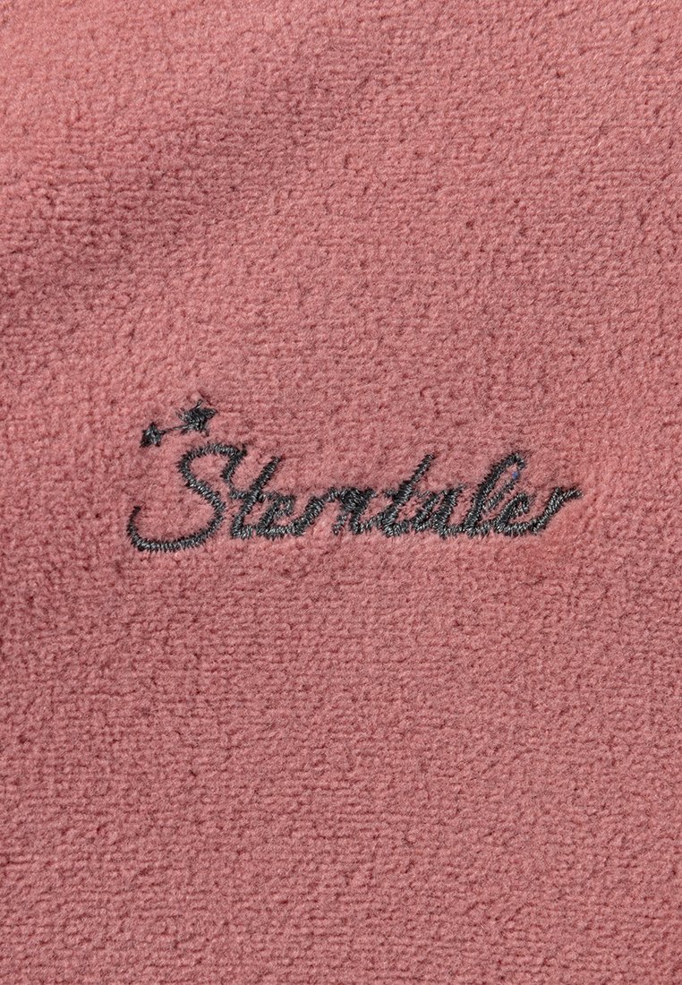 Rosa Fleece-Stoff mit schwarzem gesticktem Text "Stortales" und zwei kleinen Sternen darüber. Weiche Textur mit einer gleichmäßigen Oberfläche.