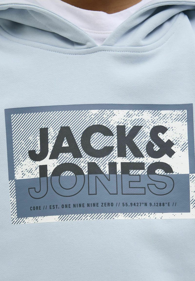 Felpa blu chiaro con cappuccio, caratterizzata da una grafica rettangolare grigia che mostra il testo "JACK & JONES" con un motivo a strisce e coordinate geografiche.