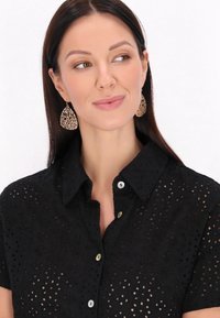 Camicia nera ricamata con maniche corte, caratterizzata da bottoni in tonalità contrastanti, con un motivo perforato e un colletto.