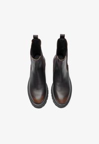 Botas de cuero marrón hasta el tobillo con un acabado suave, paneles laterales elásticos y una suela negra resistente. Presenta costuras mínimas y lengüetas para facilitar el calzado.