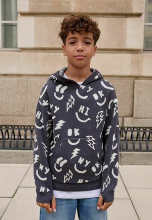 Grijze hoodie met witte grafische patronen, waaronder glimlachen, bliksemschichten en tekst. Zacht katoen, voorzak en geribde manchetten.