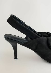 Escarpin à bride arrière noir avec un bout pointu, dessus en tissu doux, et un talon aiguille élégant et fin. Caractérisé par un détail de nœud froncé à l'avant.