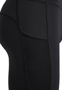 Svarta träningsleggings med ett mjukt tyg och ett texturerat nätpanel på sidan. Förstärkt sömnad ger hållbarhet.