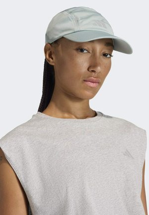 Lichtblauwe baseballpet met een gestructureerde afwerking en een gebogen rand, gecombineerd met een grijze mouwloze shirt. Minimale branding zichtbaar.