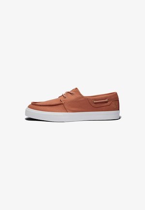 Buty płócienne w kolorze koralowym, z zaokrąglonym czubkiem, białą gumową podeszwą i sznurowaniem z przodu. Posiadają tłoczone logo oraz dekoracyjne szwy po bokach.