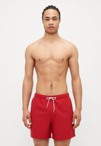 Shorts de bain rouges avec une taille élastique et un cordon de serrage blanc, présentant un design simple et une texture lisse. Pas de motifs ou d'accents supplémentaires.
