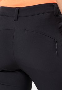 Black athletic pants feature a slim fit, elastic waistband, and a small zippered pocket on the back for secure storage.