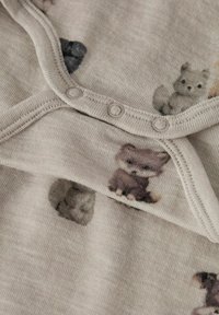 Lichtbeige stof met een zachte textuur, voorzien van een herhalend patroon van kleine dierenillustraties. Drukknoopjes langs de rand.