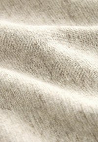 Lys beige tekstureret stof med et subtilt vævemønster, der har bløde, glatte fibre og lette farvevariationer.