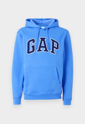 Sinine kapuutsiga džemper esitaskuga ja tumelõuendil rindkere kohal valge ääristusega tumelilla "GAP" kirjaga.