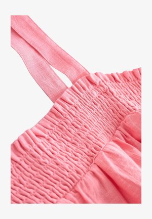 Vestito di cotone rosa con corpetto arricciato e spalline regolabili. Il tessuto ha una texture morbida con un dettaglio di orlo arricciato e svolazzante.