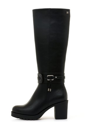 Bota negra hasta la rodilla hecha de cuero suave, con un tacón robusto y dos correas decorativas con acentos metálicos. Suela texturizada para mayor agarre.