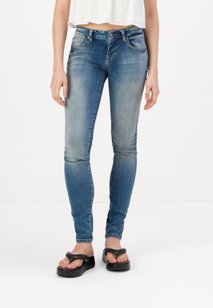 Faded blue skinny jeans featuring a classic five-pocket design. Made of denim with a smooth texture, paired with black flip-flops.