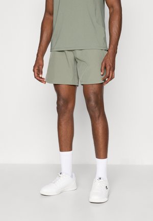 Light green athletic shorts paired with a matching top, featuring breathable fabric, and white sneakers with ribbed white socks.
