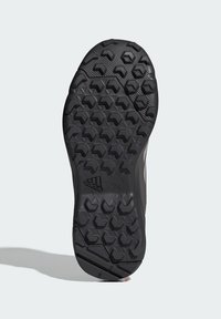 Suela de goma negra con un patrón de agarre texturizado que presenta formas hexagonales y triangulares, diseñado para proporcionar tracción en diversas superficies.