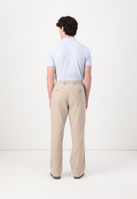 Light blue polo shirt paired with beige linen pants. Pants feature an elastic waistband and subtle back pockets. Smooth, relaxed fit.