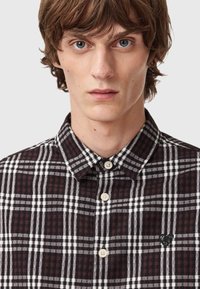Camicia a quadri in rosso scuro e nero, con strisce bianche, colletto button-down e un piccolo logo ricamato sul petto.