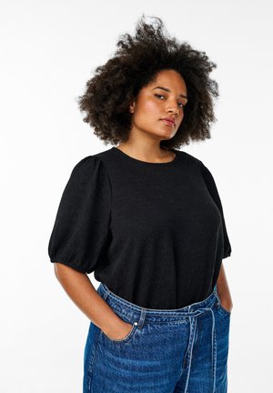 Black, textured top with short puff sleeves, paired with high-waisted blue denim jeans featuring a front tie and side pockets.