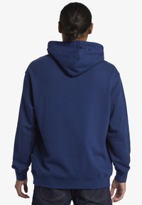 Sudadera azul marino con una gran capucha forrada, puños y dobladillo de canalé. Fabricada con un material suave, que muestra una textura lisa.
